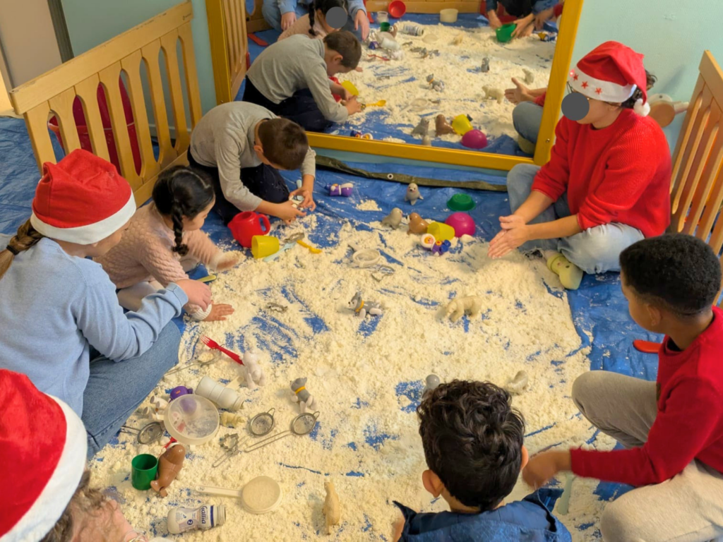 Enfants de la crèche de Montchat Botté jouant dans un bac de neige artificielle lors de la fête de Noël 2025