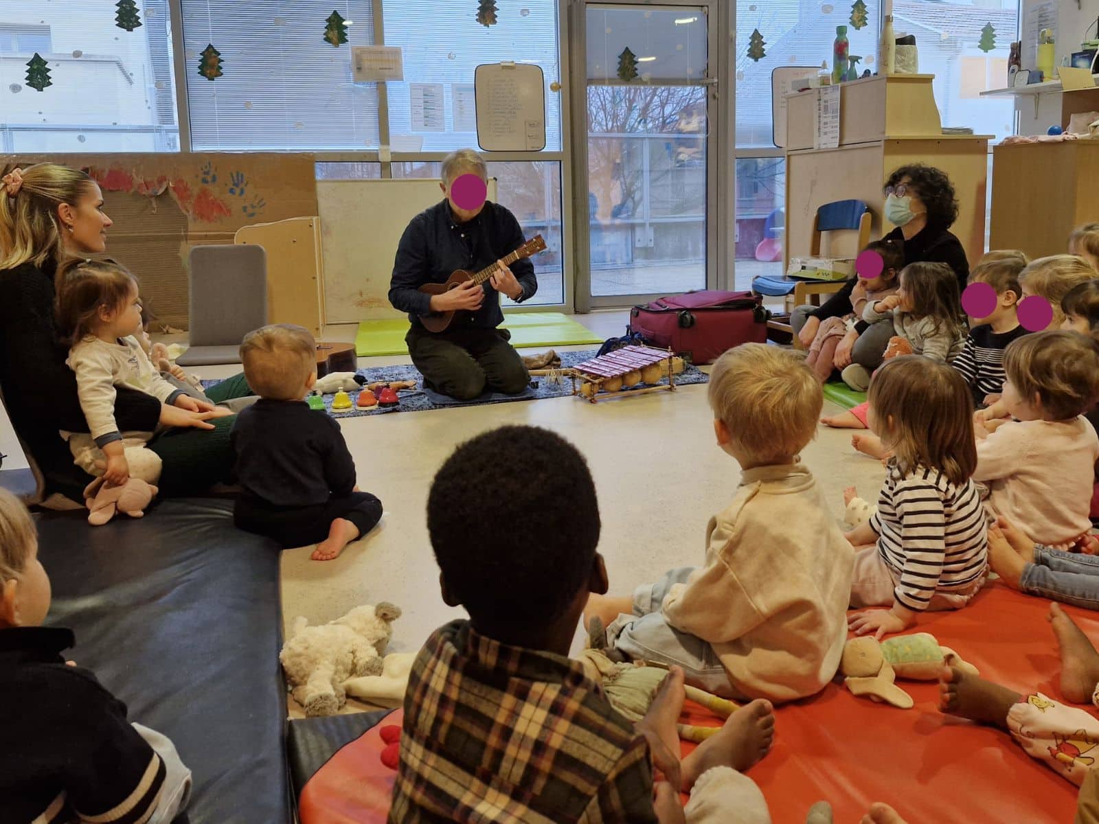 Intervenant musical jouant du ukulélé devant les enfants de la crèche des Montchatons