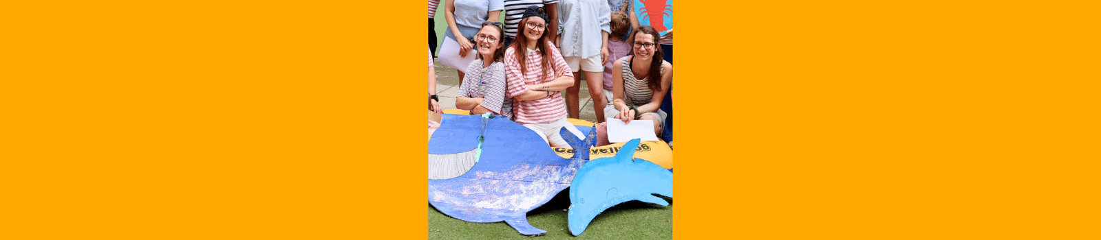 Bannière de la fête d'été de la crèche Montchat Bada à Lyon 3 : trois professionnelles derrière une baleine et un dauphin en carton peint